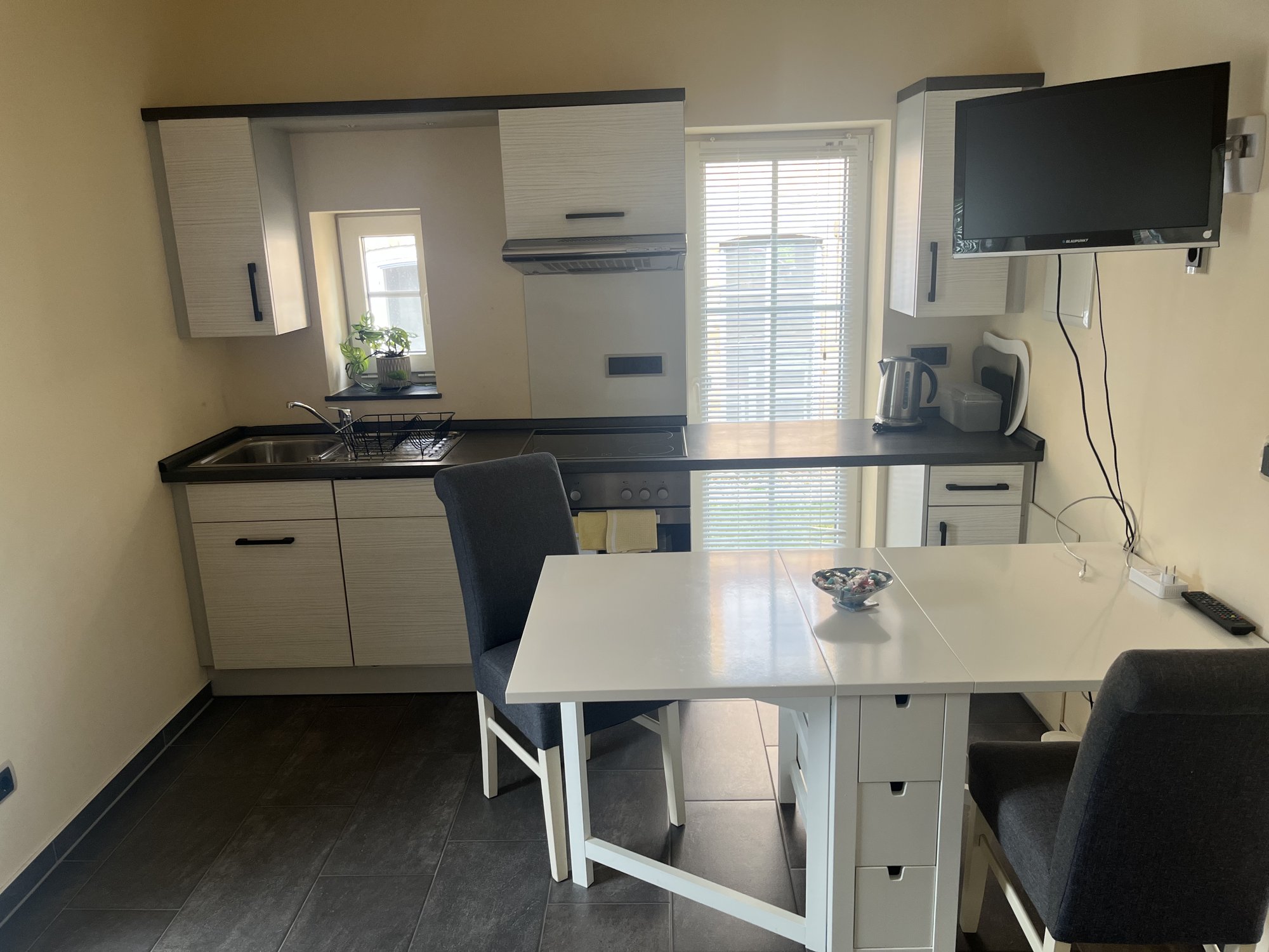 Offene Küche mit Esstisch, Herd, Spüle und Fernseher